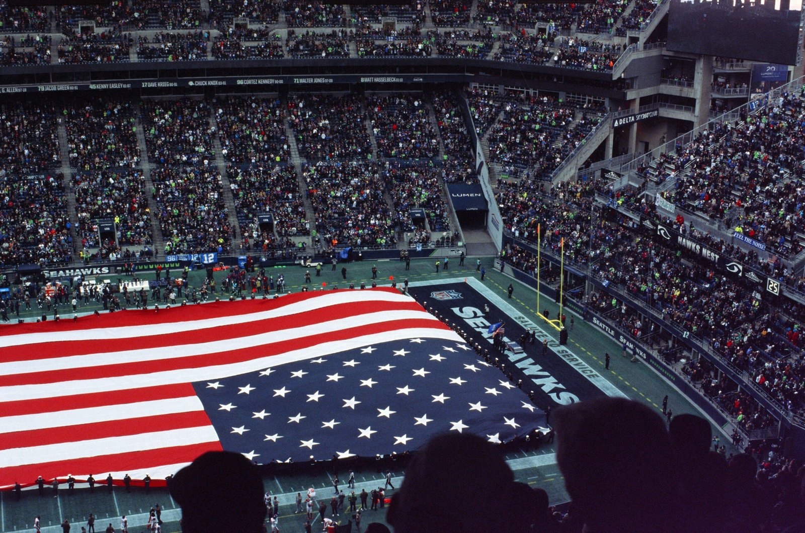 a large american flag is displayed in a stadium